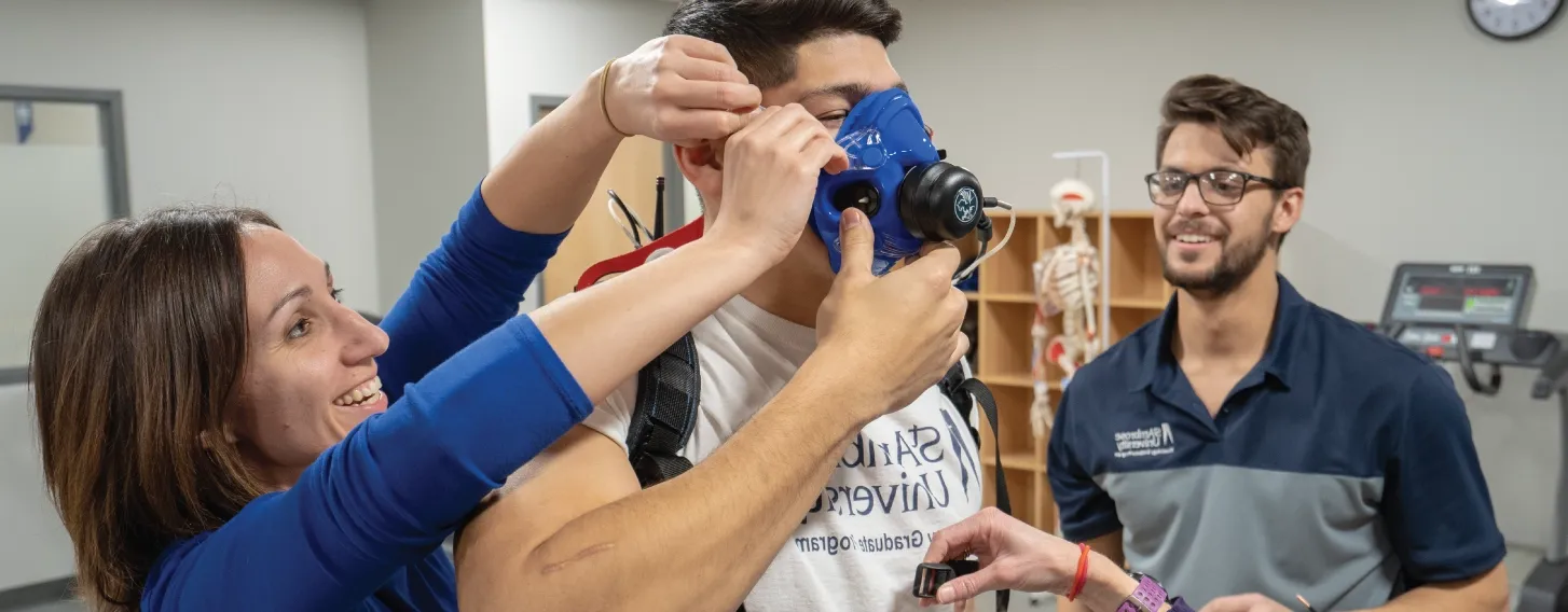 Group of kinesiology students and teacher practicing assessment in a lab.